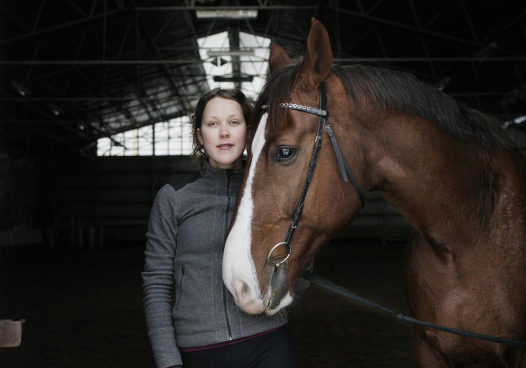 Anna-Lyydia ja hevonen vierekkäin ratsastushallissa.